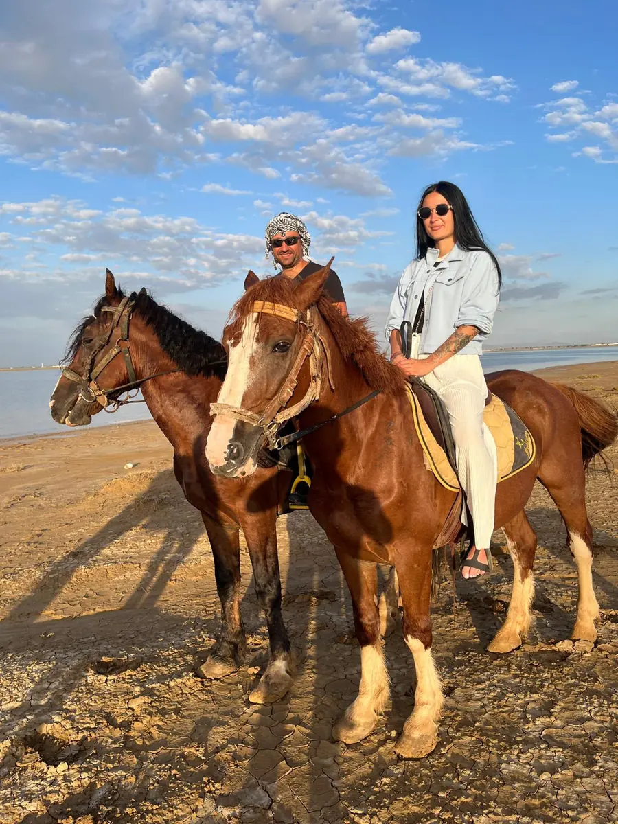 Un couple à cheval au bord de la lagune sous un ciel bleu